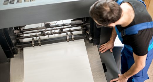 Worker following a printing process on the offset machine at the manufacturing